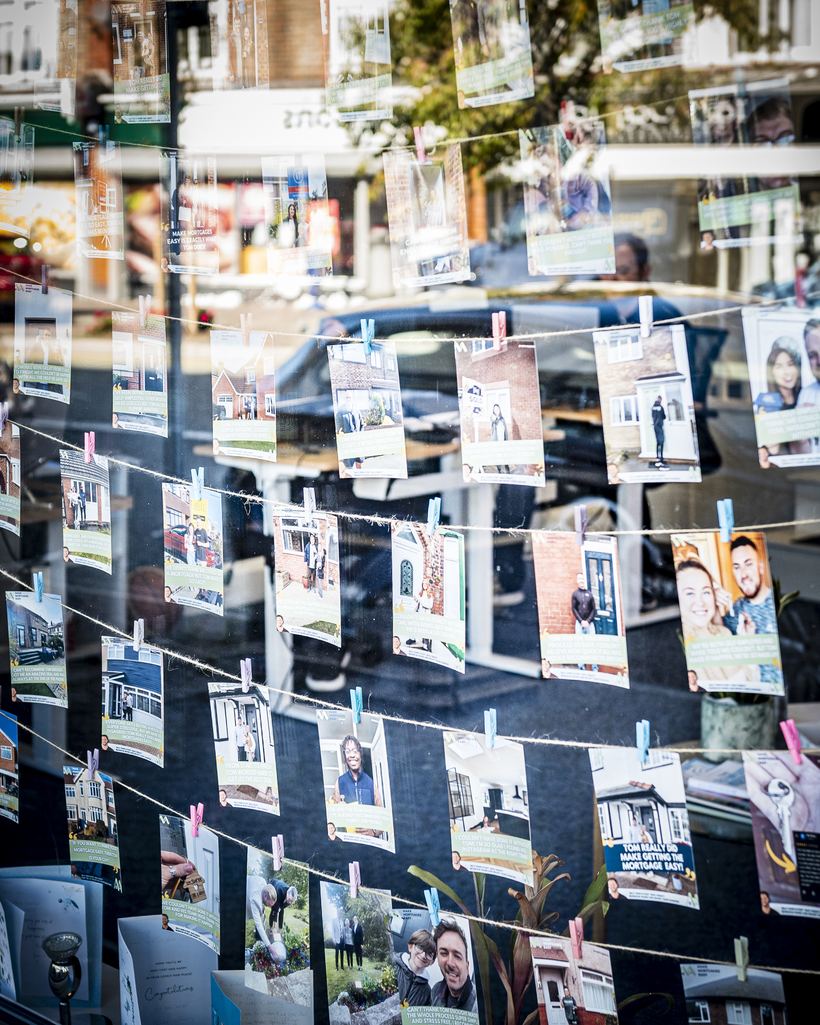 The Make Mortgages Easy office window, hung with photographs and thank-you notes from clients who have completed on their homes