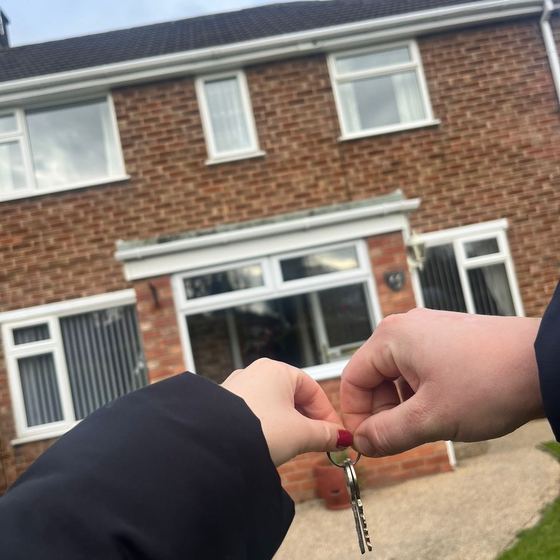 Keys being handed over outside a newly purchased home